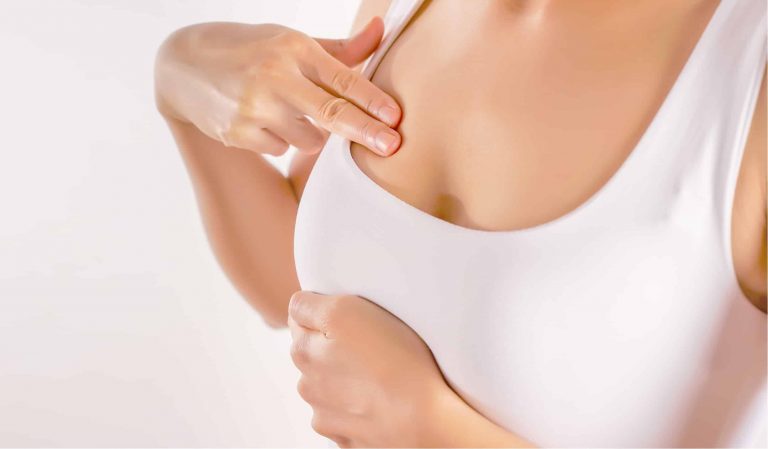 A woman performing a breast self-exam to check for signs of breast cancer