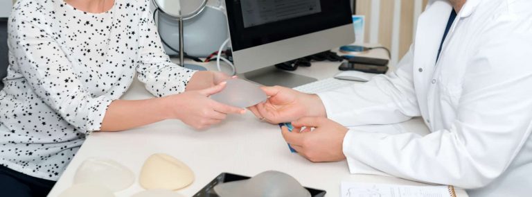 A woman holding a gummy bear implant while talking to her plastic surgeon