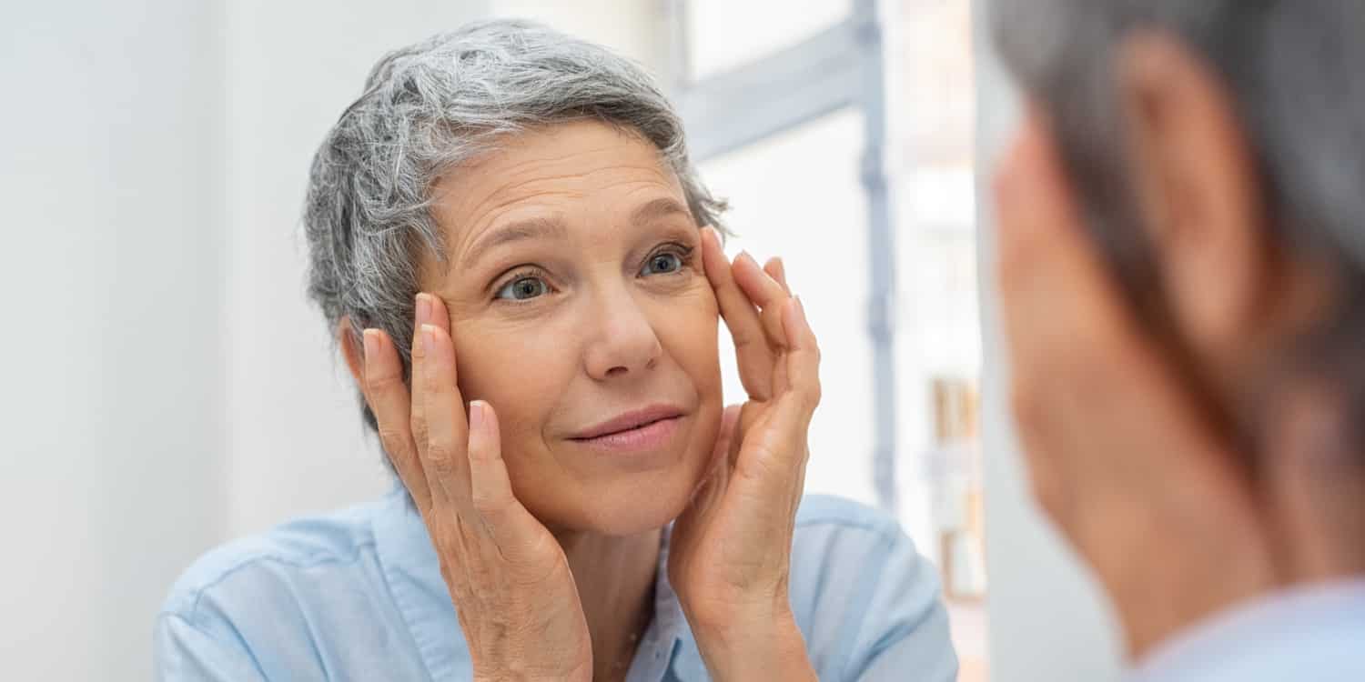 A woman examining her face for signs of blepharoplasty scarring