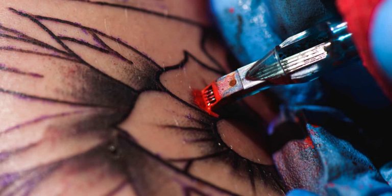 A person getting a tattoo over a plastic surgery scar