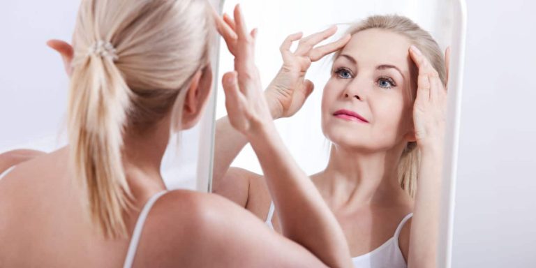 A mature woman examining her face for facelift scars