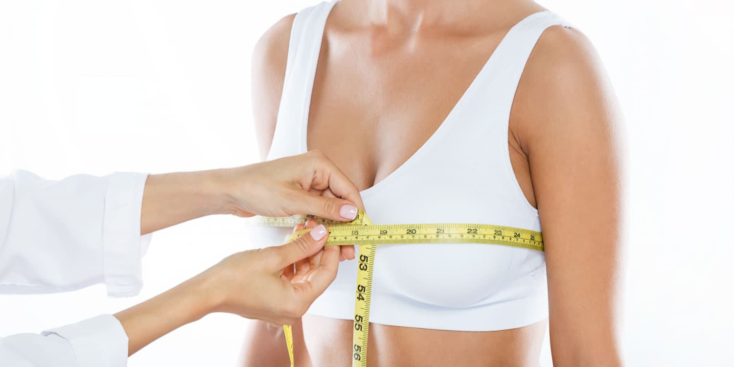 A doctor measuring a woman's breasts after a reduction surgery